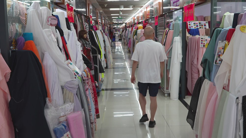 원단 시장 복도 — 양쪽에 천을 길게 걸어 둔 원단 가게들